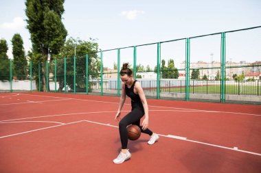 Atletik basketbolcu basketbol sahasında topu sürüyor. Basketbol, oyun, eğlence, açık hava stencilling.