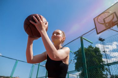 Atletik bayan basketbolcu topu ağlara atıyor..