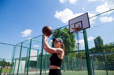 Atletik bayan basketbolcu topu ağlara atıyor..