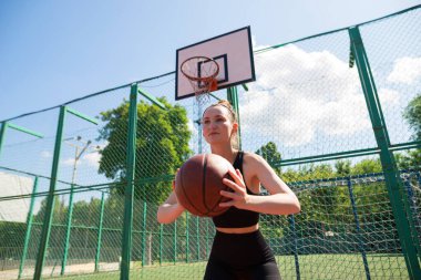 Atletik bayan basketbolcu topu ağlara atıyor..