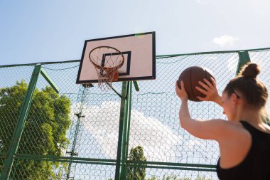 Atletik bayan basketbolcu topu ağlara atıyor..