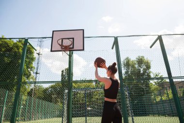 Atletik bayan basketbolcu topu ağlara atıyor..