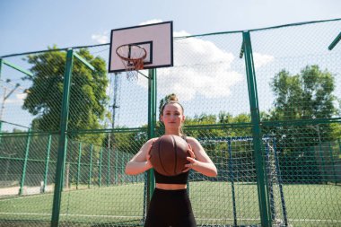 Atletik bayan basketbolcu topu ağlara atıyor..