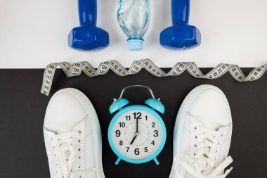 Beyaz saatli dambıl spor ayakkabıları ve diğer spor aletlerinin en üstteki fotoğrafı. Yoga fitness spor zayıflama konsepti