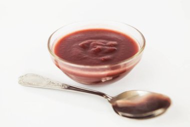 Beyaz arka planda cam bir plakada erik reçeli, yakın plan.