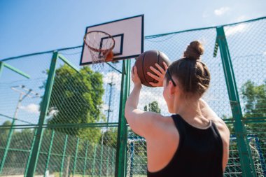 Atletik bayan basketbolcu topu ağlara atıyor..