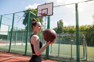 Basketbol sahasında basketbol oynayan genç bir kız, aktif bir hafta sonu..