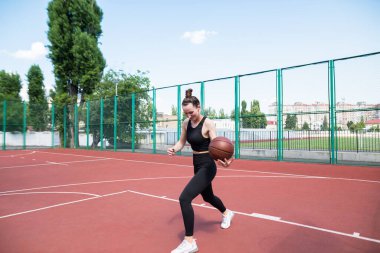 Atletik basketbolcu basketbol sahasında topu sürüyor. Basketbol, oyun, eğlence, açık hava stencilling.