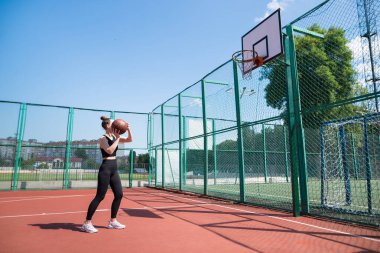 Atletik bayan basketbolcu topu ağlara atıyor..