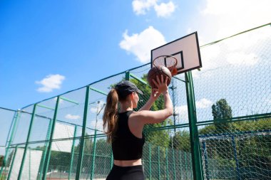 Atletik bayan basketbolcu topu ağlara atıyor..