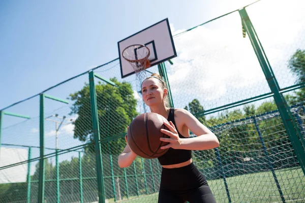 Atletik bayan basketbolcu topu ağlara atıyor..