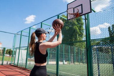 Atletik bayan basketbolcu topu ağlara atıyor..