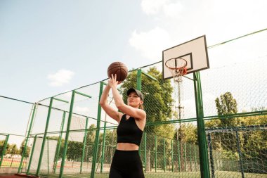 Atletik bayan basketbolcu topu ağlara atıyor..