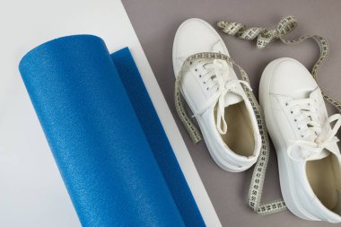 Beyaz spor ayakkabıları ve spor paspasının en üstteki fotoğrafı. Spor, yoga, fitness konsepti.