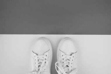 Siyah beyaz arka plandaki beyaz spor ayakkabılarının fotokopi alanı ile en üstteki görünümü.