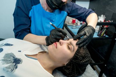 Makyaj ustası müşteri için kalıcı kaş makyajı prosedürünü gerçekleştirir