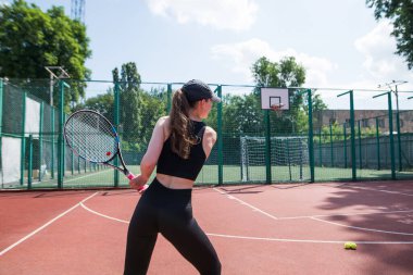 Raketli ve tenis toplu spor kızı. Güzel bir genç kız egzersiz yapıyor. Tenisçi servis atmaya hazırlanıyor..