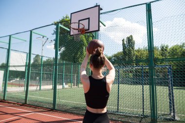 Atletik bayan basketbolcu topu ağlara atıyor..