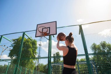 Atletik bayan basketbolcu topu ağlara atıyor..
