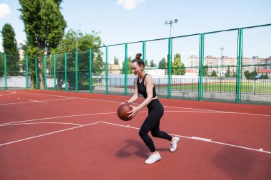 Atletik basketbolcu basketbol sahasında topu sürüyor. Basketbol, oyun, eğlence, açık hava stencilling.