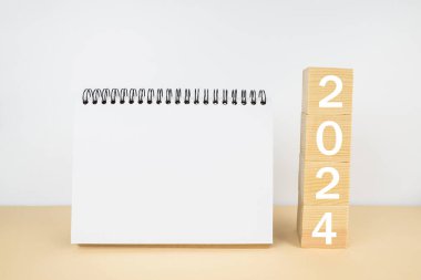 Masanın üzerinde boş bir not defteri olan 2024 küp. Takvim ya da düzen. Yeni yıl konsepti, çözüm, hedef, plan, sağlık.