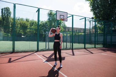 Basketbol sahasında basketbol oynayan genç bir kız, aktif bir hafta sonu..