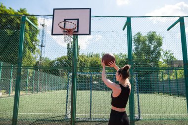 Atletik bayan basketbolcu topu ağlara atıyor..