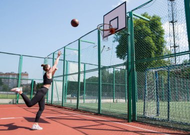 Atletik bayan basketbolcu topu ağlara atıyor..