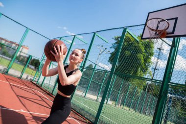 Atletik bayan basketbolcu topu ağlara atıyor..