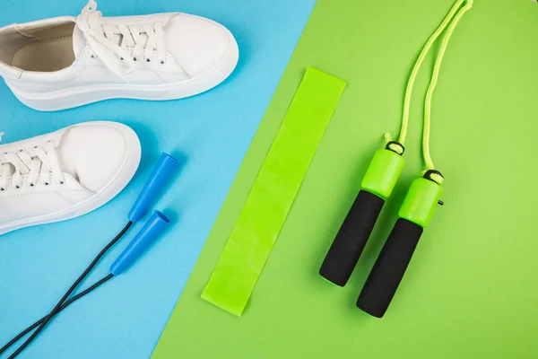 The concept of sports accessories. Photo of blue dumbbells and a blue exercise mat, white sneakers and other sports equipment. The concept of sport, fitness, yoga, weight loss, healthy lifestyle