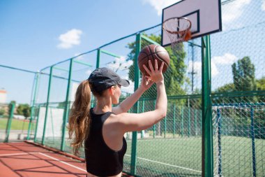 Atletik bayan basketbolcu topu ağlara atıyor..