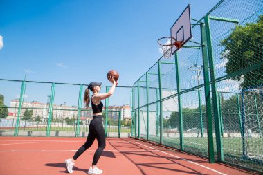 Atletik bayan basketbolcu topu ağlara atıyor..