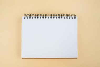 Bej arka planda boş beyaz bir not defteri. Boşluğu, düzeni, takvimi, şablonu, metin için yeri kopyala.