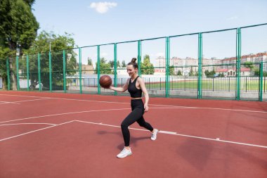 Atletik basketbolcu basketbol sahasında topu sürüyor. Basketbol, oyun, eğlence, açık hava stencilling.