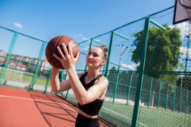 Atletik bayan basketbolcu topu ağlara atıyor..