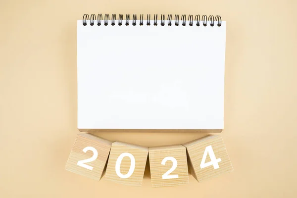 2024 time for new start. white paper and 2024 cubes. wooden table background. New Year plans for 2024, blank space on notepad, mockup calendar. Start new year 2024 with goal plan