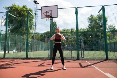 Atletik bayan basketbolcu topu ağlara atıyor..