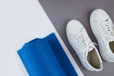 Yuvarlak mavi yoga minderi, beyaz spor ayakkabılar. sağlıklı yaşam tarzı, spor ve egzersiz konsepti. Gri arkaplan.