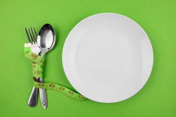 在绿色背景上测量带子 盘子和餐具 饮食概念 体重减轻 — 图库照片