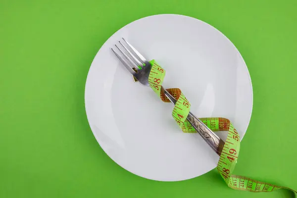 グリーンの背景にテープ プレート カトラリーを測定します ダイエット 減量の概念 — ストック写真