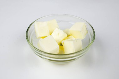 Beyaz arka planda cam bir kasede tereyağı.