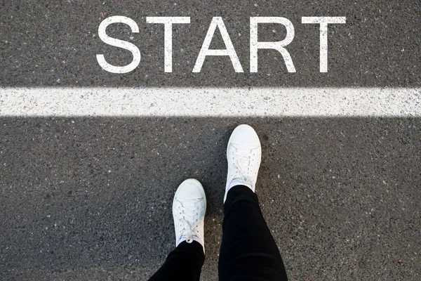 Word Start asfalt bir yolda, ayakları ve ayakkabıları ile yazılmış. Konseptin başlangıcı. başlangıçtan önce bacaklar