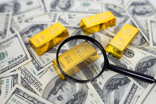 gold bars with a magnifying glass on dollars. Financial saving concept. gold and dollars.