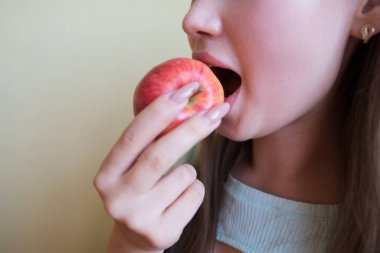 Güzel bir kadın kırmızı elma yiyor, yakın plan. Kırpılmış fotoğraf.