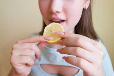 Limon yiyen güzel bir kadın, yakın plan. Kırpılmış fotoğraf.