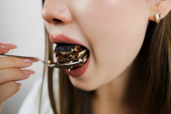 woman eating cake, close-up. Cropped photo.