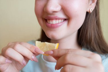 young beautiful girl eating lemon, close-up, crop photo.