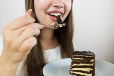 young beautiful girl eating cake, close-up, crop photo.