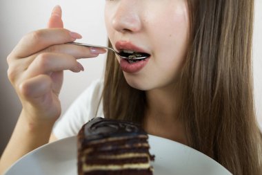 young beautiful girl eating cake, close-up, crop photo.