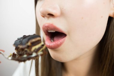 young beautiful girl eating cake, close-up, crop photo.